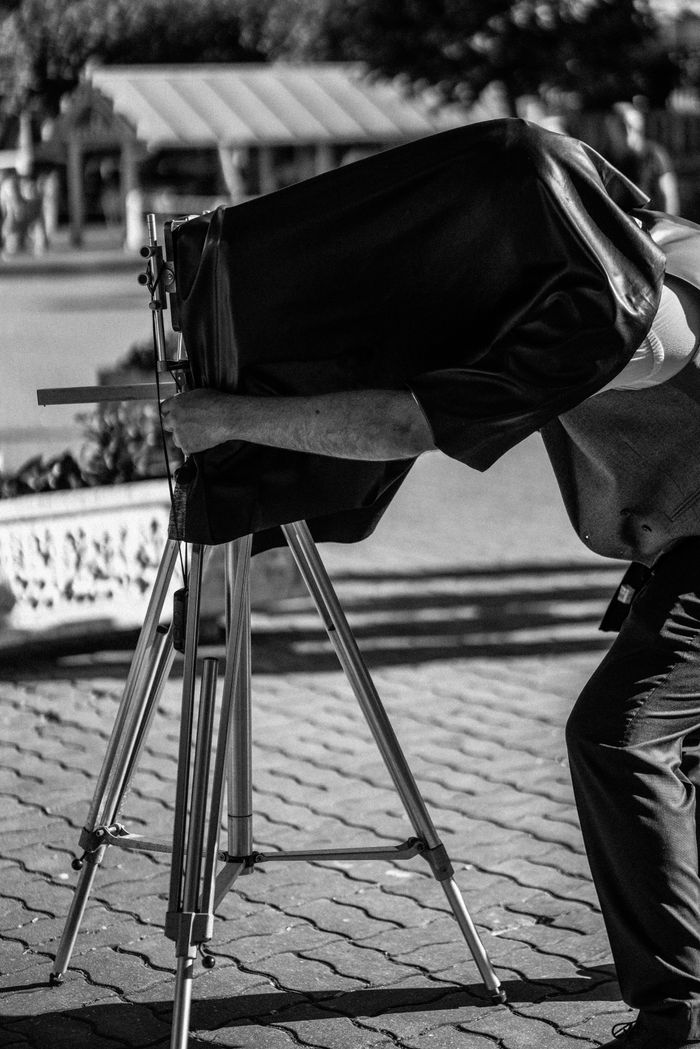 about-us-01 Black and white photo of a vintage photographer using a large format camera outdoors.